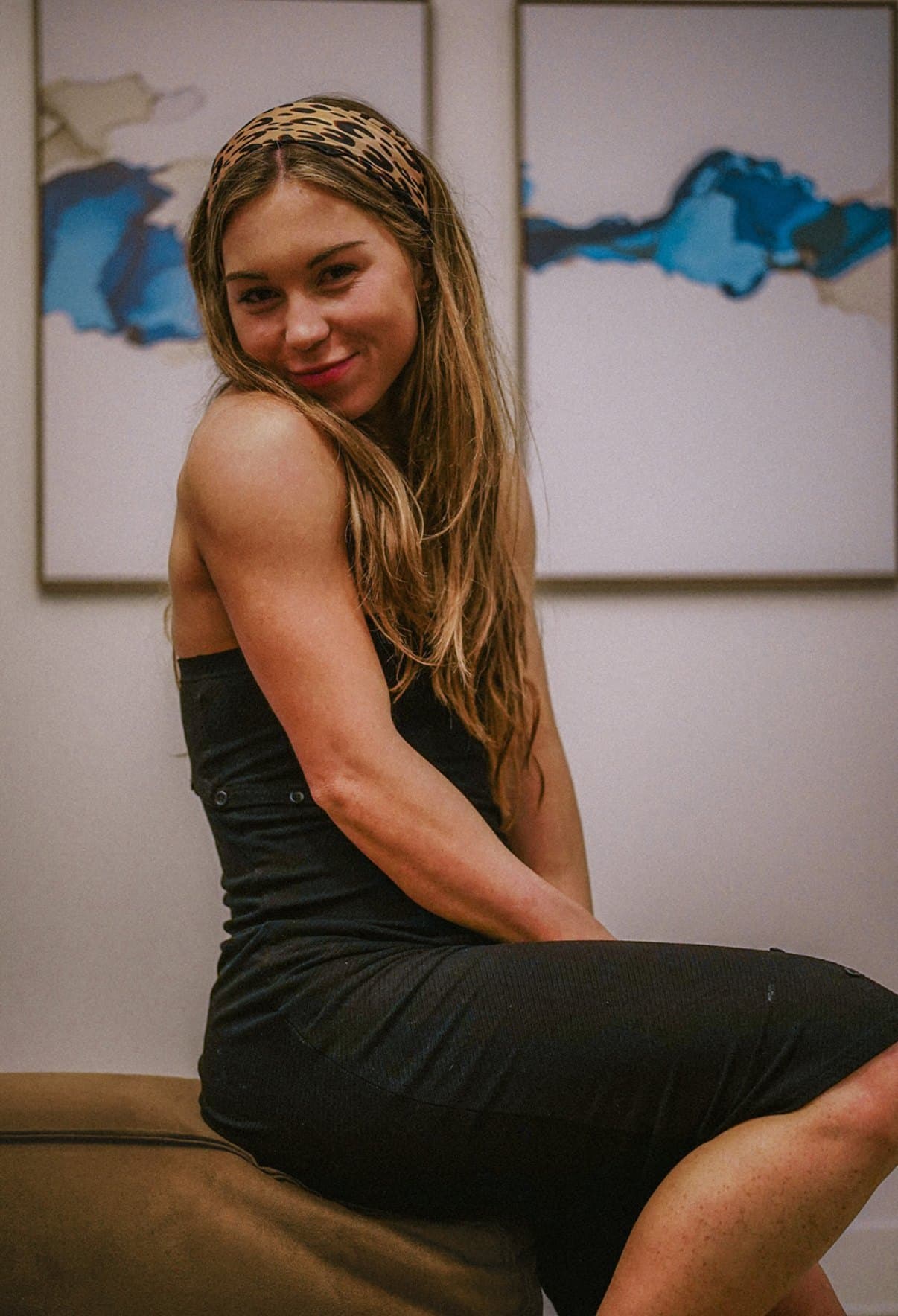 Danielle Kusenberger smiling in a black dress and leopard headband